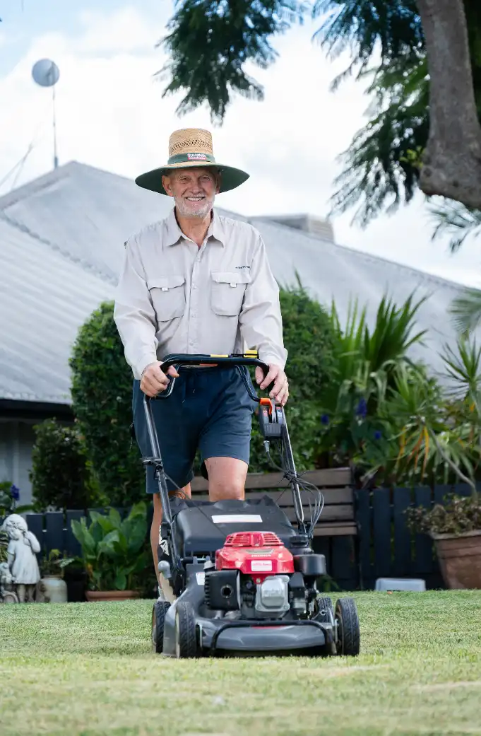 Gardening volunteer walks down path with her equipment and bag.